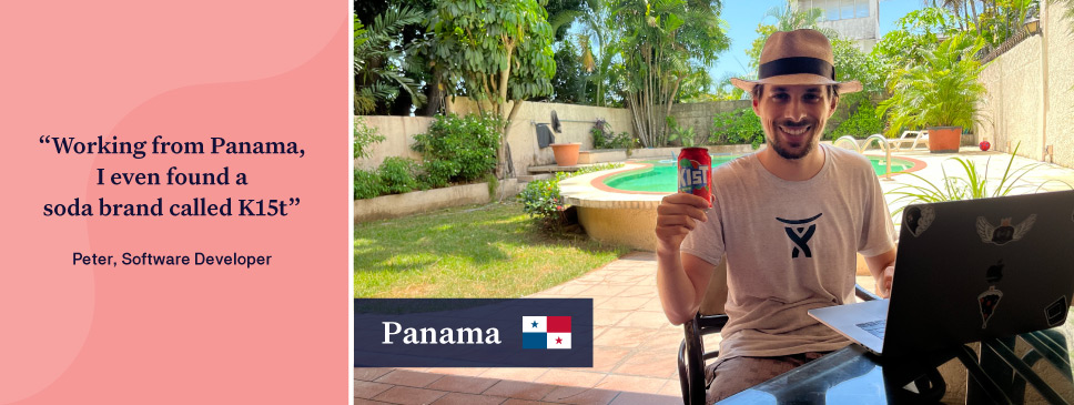 Man with a sun hat holding a lemonade can sitting in a garden in front of a laptop